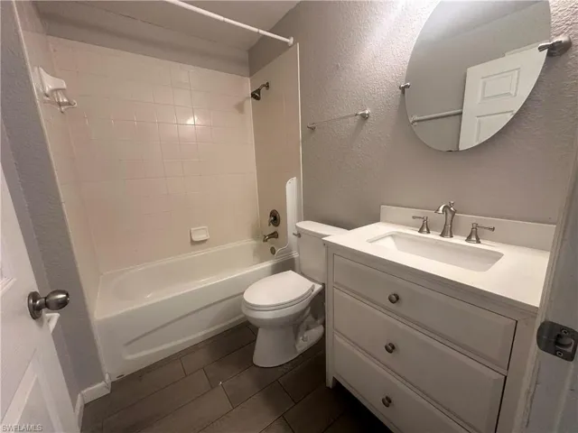 Bathroom featuring a textured wall, vanity, and bathtub / shower combination
