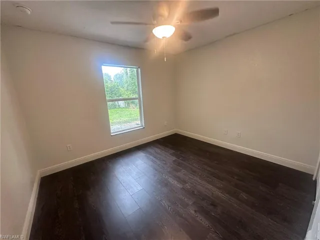 Spare room featuring dark wood finished floors, ceiling fan, and a smoke detector