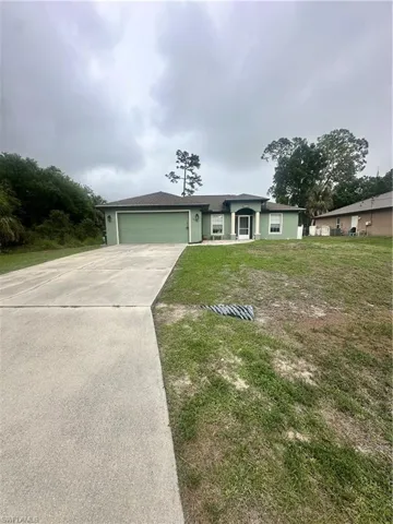Single story home with an attached garage, driveway, and a front lawn