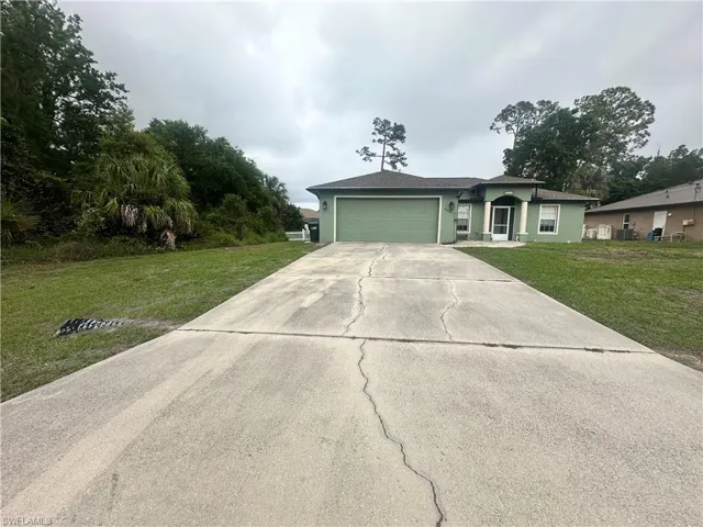 Ranch-style house featuring a front lawn, a garage, concrete driveway, and stucco siding