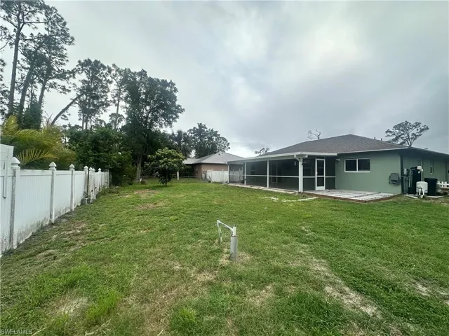 Fenced backyard with a sunroom and a patio area