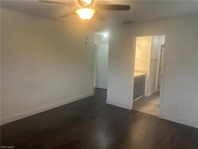Unfurnished bedroom with dark wood-style floors, a ceiling fan, and ensuite bathroom
