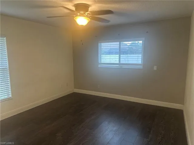 Spare room featuring dark wood-style floors, ceiling fan, and a textured ceiling