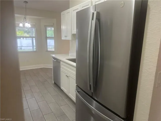 Kitchen featuring stainless steel appliances, white cabinets, wood tiled floors, and light stone counters