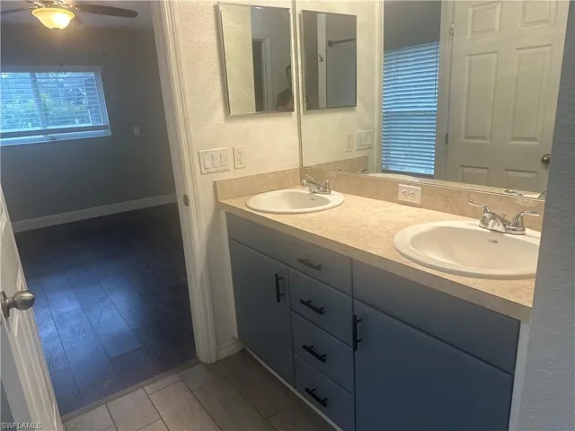 Bathroom featuring a textured wall, light wood-style flooring, double vanity, and a ceiling fan