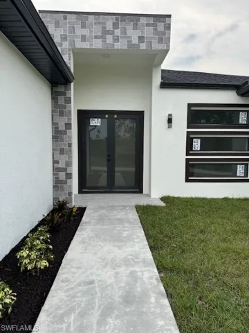 Entrance to property with french doors and a lawn