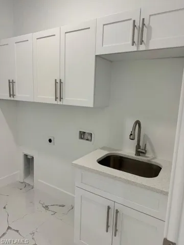 Laundry area with washer hookup, hookup for an electric dryer, sink, and cabinets
