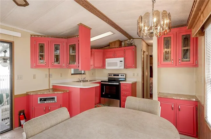 Kitchen with stainless steel range with electric cooktop, vaulted ceiling with beams, plenty of natural light, and sink