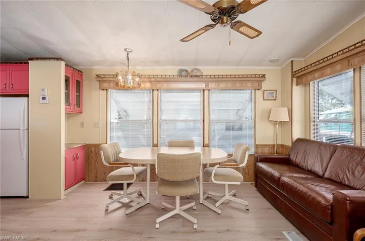 Dining area with ceiling fan with notable chandelier, vaulted ceiling, light hardwood / wood-style flooring, and crown molding