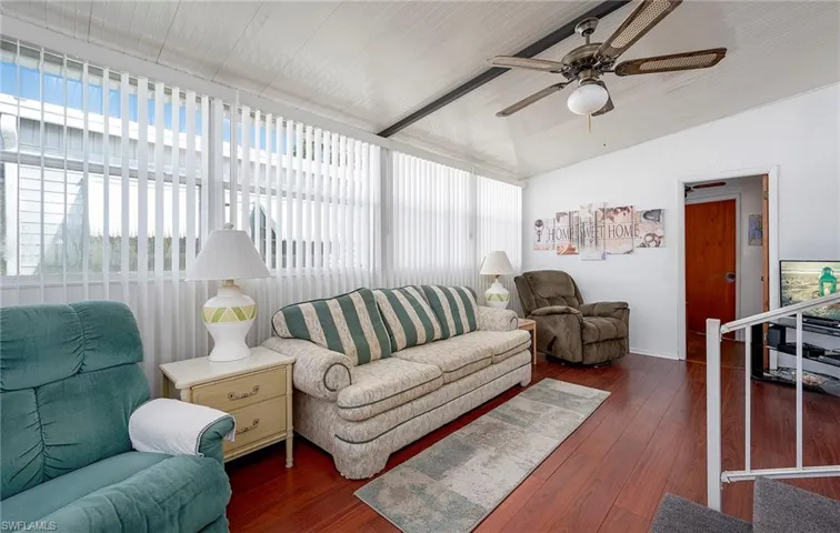 Living room featuring ceiling fan, vaulted ceiling with beams, and dark hardwood / wood-style floors