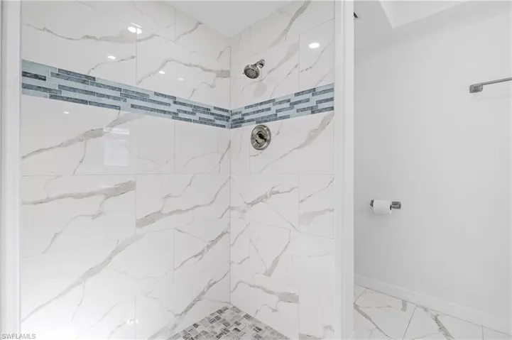 Full bath featuring a marble finish shower and light marble finish floors