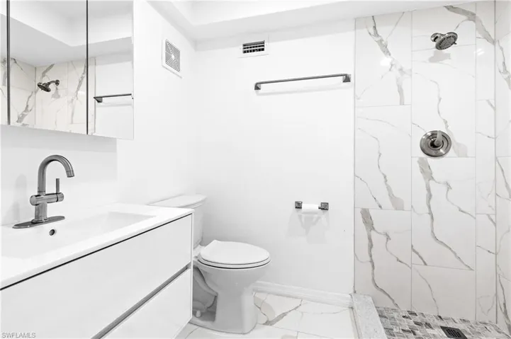 Bathroom featuring a marble finish shower and vanity