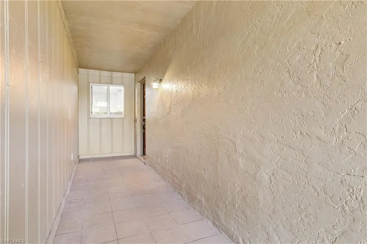 Hall featuring a textured wall and tile patterned flooring