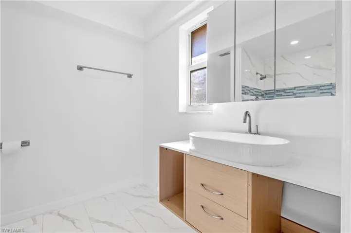 Full bath with vanity, a tile shower, and light marble finish flooring