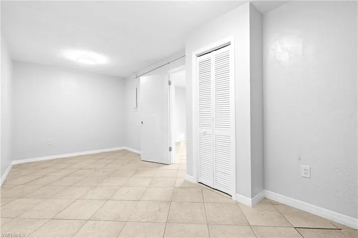 Unfurnished bedroom featuring a textured wall, a closet, and light tile patterned floors