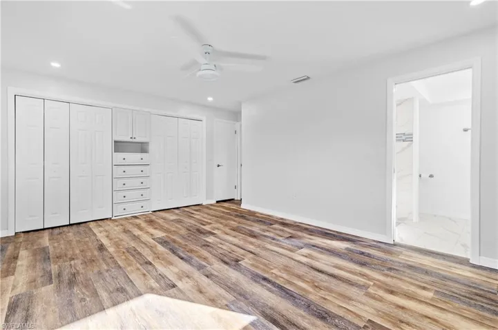 Unfurnished bedroom with multiple closets, a ceiling fan, connected bathroom, light wood-style flooring, and recessed lighting