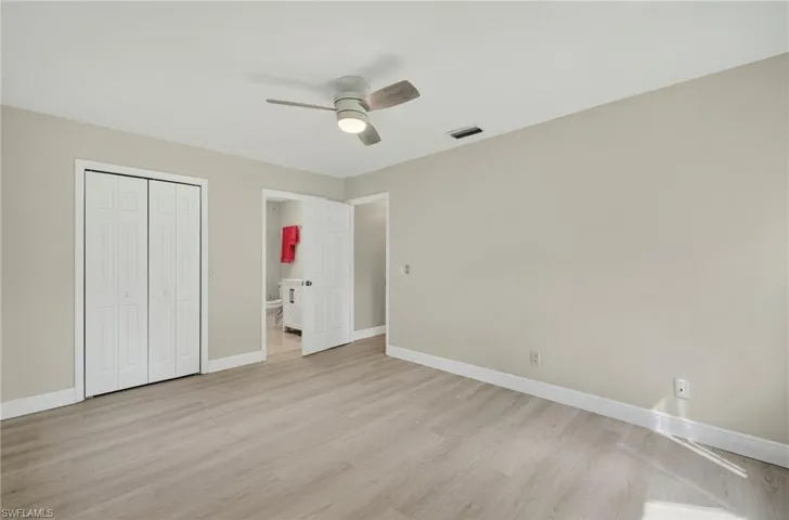 Unfurnished bedroom featuring light wood-type flooring, a closet, ceiling fan, and connected bathroom