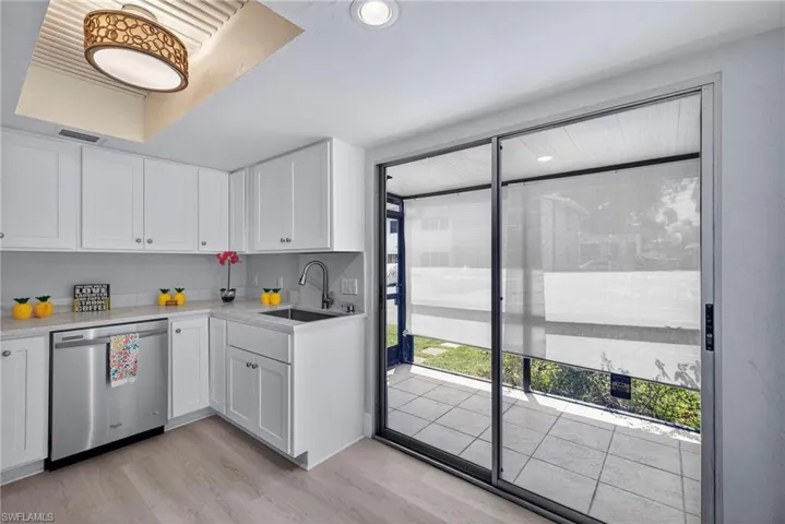 Kitchen featuring dishwasher, light wood-type flooring, white cabinets, light stone counters, and recessed lighting