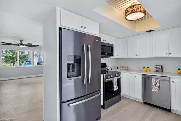 Kitchen with stainless steel appliances, white cabinets, and light wood finished floors