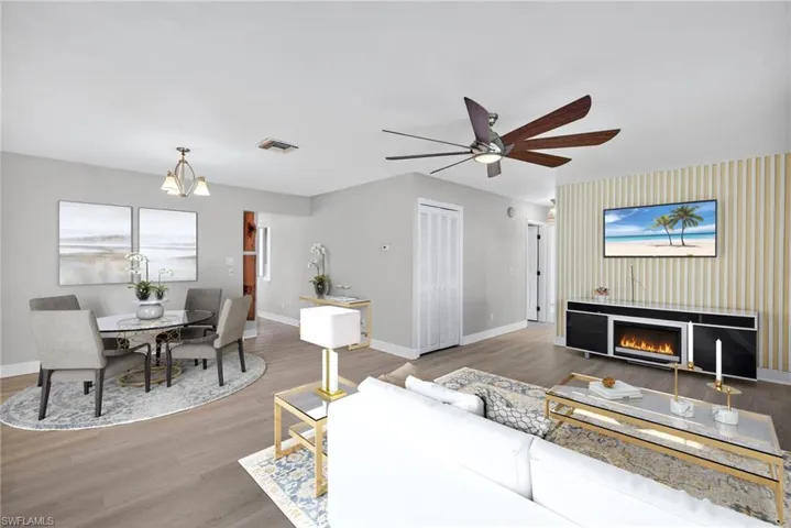 Living area with wood finished floors, a warm lit fireplace, a chandelier, and a ceiling fan
