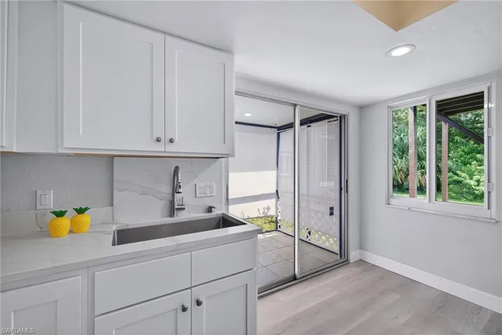 Bar with light stone counters, white cabinetry, light wood-style flooring, and recessed lighting