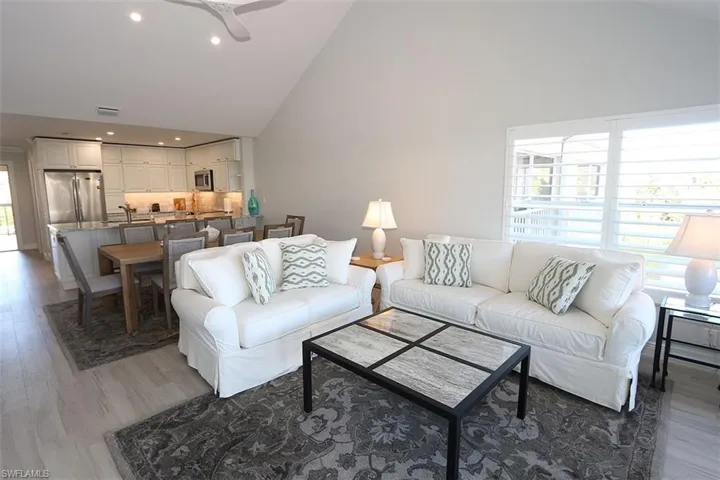 Living room with high vaulted ceiling, light wood finished floors, recessed lighting, and ceiling fan
