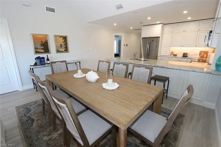 Dining space with light wood-type flooring, ornamental molding, recessed lighting, and vaulted ceiling