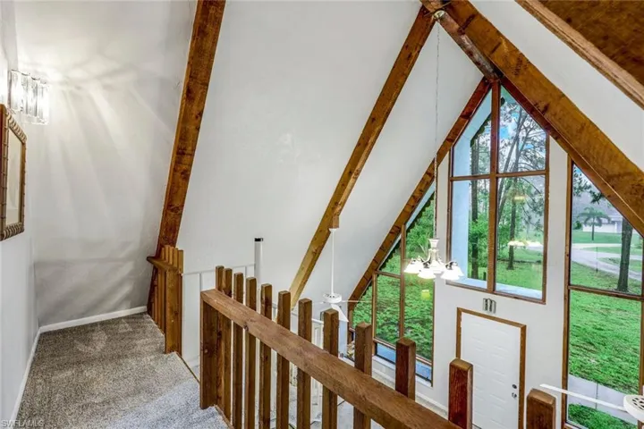 Loft balcony with beam ceiling, a chandelier, and carpet floors