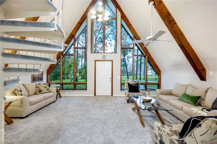 Carpeted living room featuring beam ceiling, high vaulted ceiling, and ceiling fan