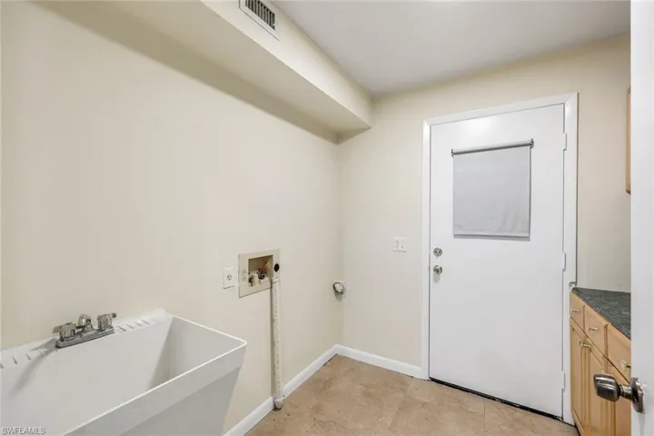 Laundry area with cabinets, sink, light tile floors, and washer hookup