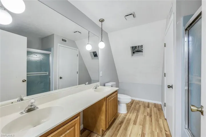 Bathroom with oversized vanity, toilet, hardwood / wood-style floors, double sink