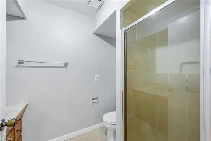 Bathroom featuring walk in shower, tile flooring, toilet, and vanity