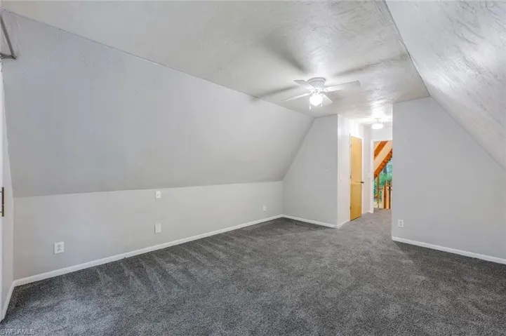 Bonus room with ceiling fan, vaulted ceiling, and carpet