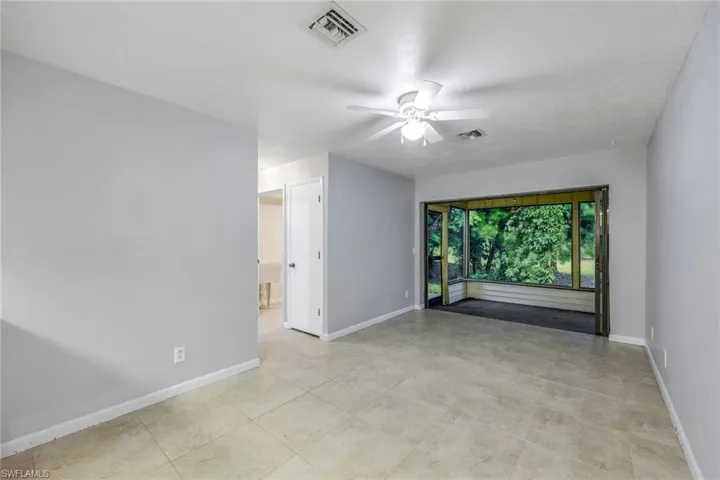 Unfurnished room with ceiling fan and light tile flooring