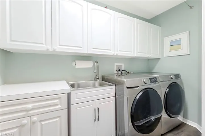 Large laundry room with additional storage, mud sink and front load washer and dryer