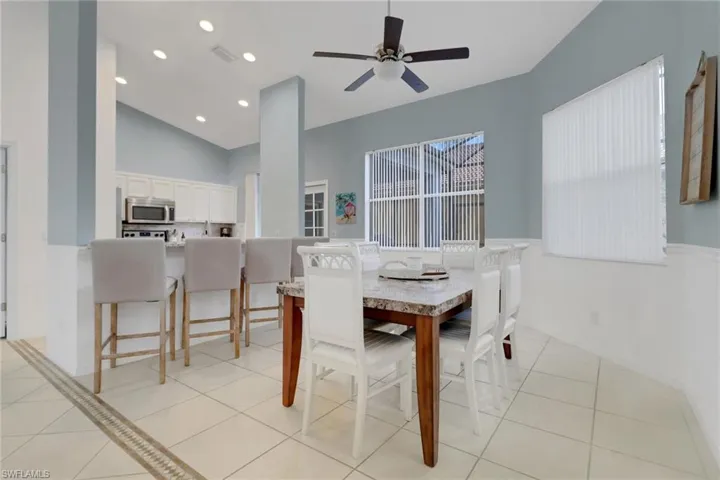 Dining area featuring a ceiling fan, light tile patterned flooring, vaulted ceiling, and recessed lighting