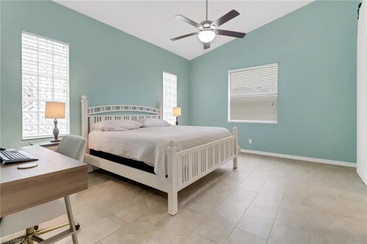 Bedroom featuring multiple windows, lofted ceiling, an office area, and ceiling fan