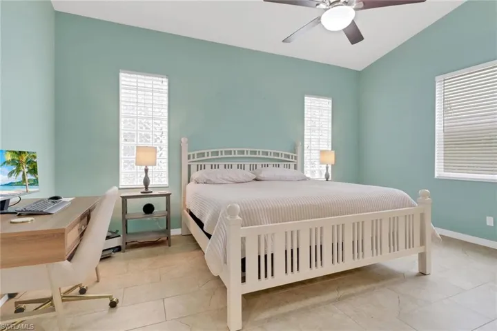 Bedroom with multiple windows, a desk, and a ceiling fan