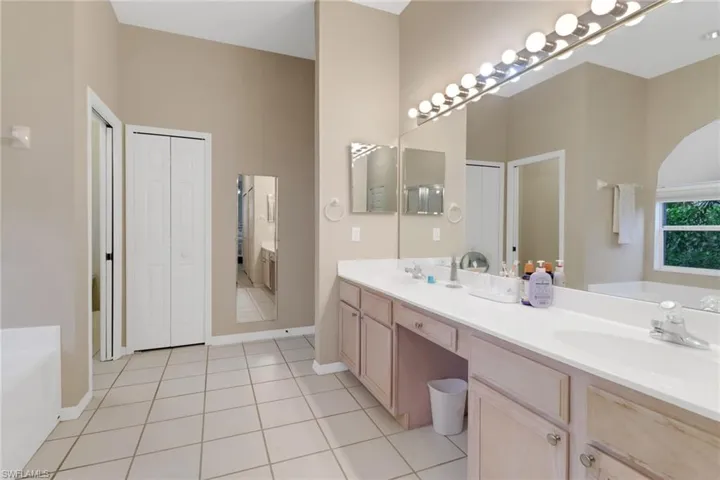 Full bathroom featuring double vanity, a bath, a closet, and tile patterned floors