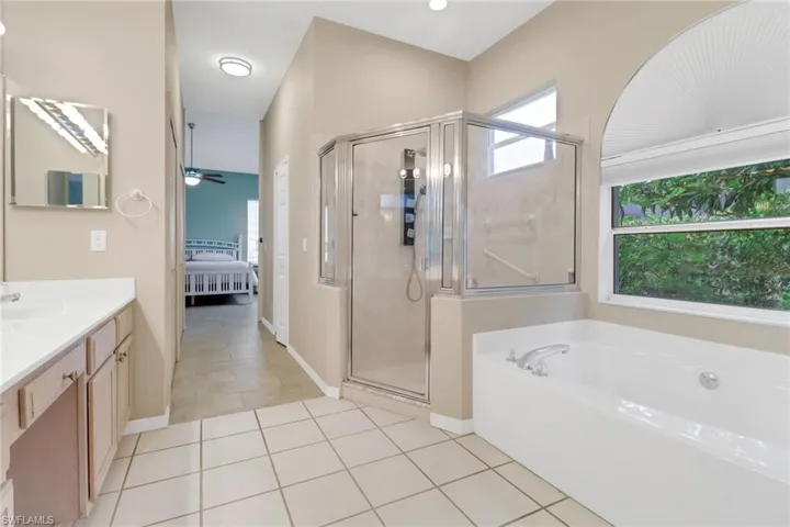 Bathroom with ensuite bath, vanity, a garden tub, a shower stall, and ceiling fan