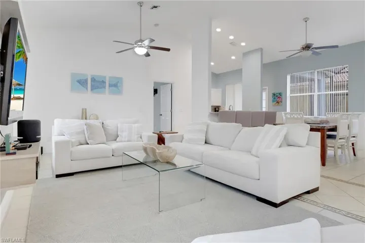 Living area with a ceiling fan, high vaulted ceiling, tile patterned flooring, and recessed lighting