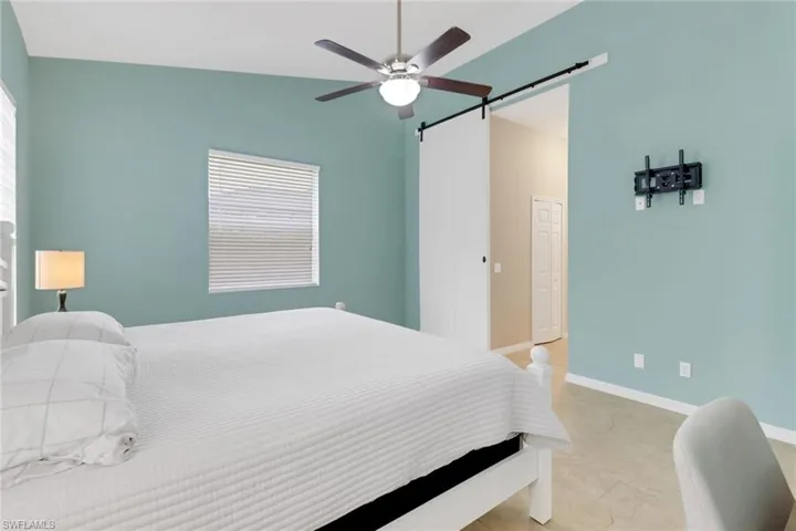 Bedroom with a barn door, ceiling fan, and lofted ceiling