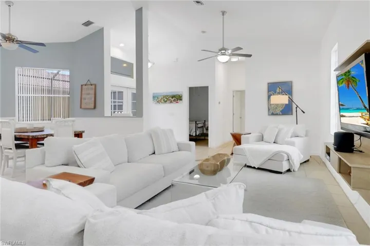 Living area with ceiling fan, high vaulted ceiling, and light tile patterned flooring
