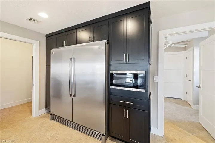 Kitchen featuring stainless steel appliances, ceiling fan, light tile patterned flooring, a textured ceiling, and dark cabinetry