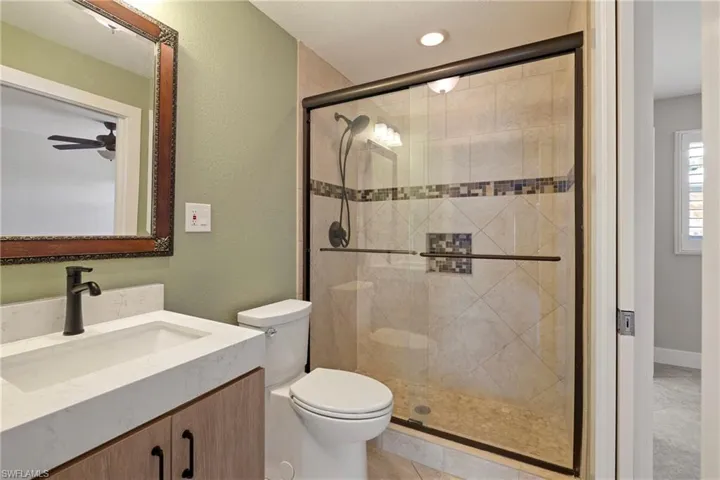 Bathroom featuring vanity, a shower stall, a textured wall, and recessed lighting
