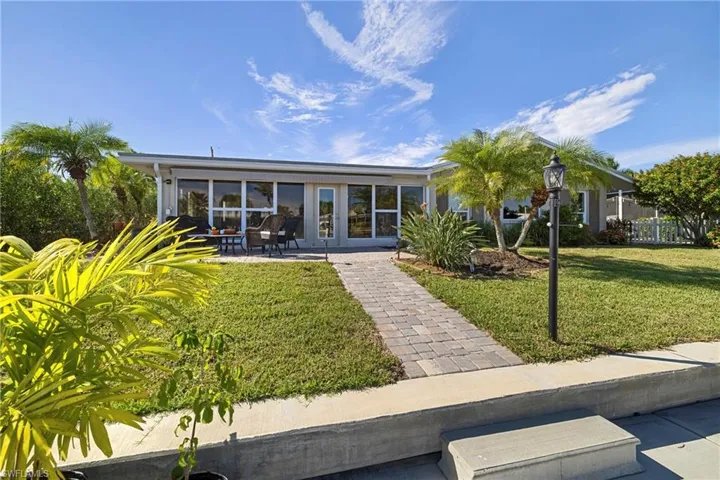 Back of house featuring a sunroom, a lawn, and a patio area
