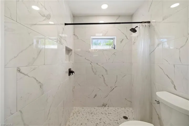 Bathroom featuring toilet and a marble finish shower