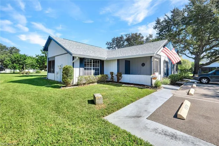 Ranch-style house featuring a shingled roof and a front yard