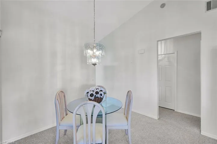 Chandeliered dining area with entry to kitchen and bedroom hallway