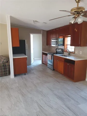 Kitchen with stainless steel appliances, a ceiling fan, light countertops, and a textured ceiling